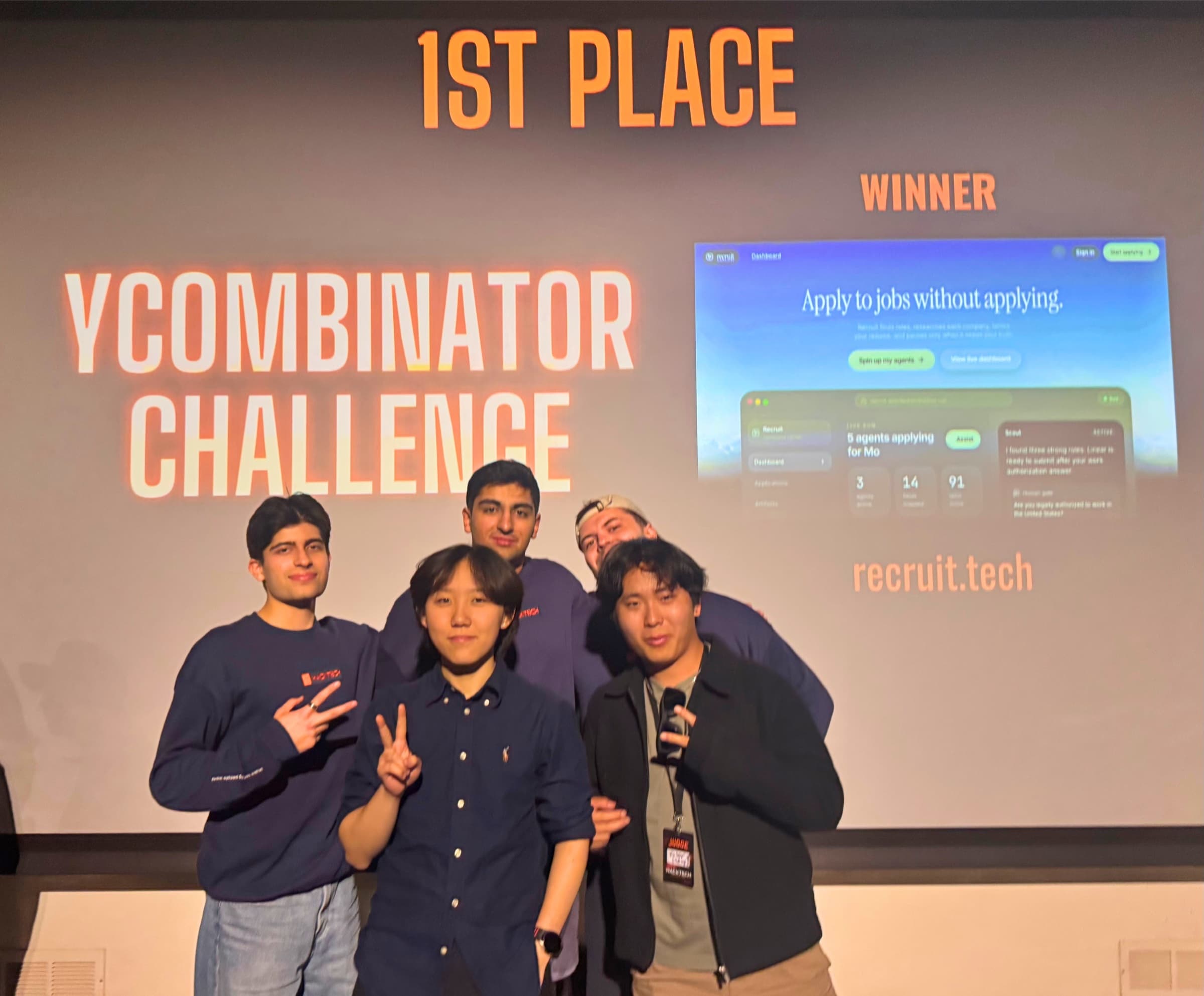 Mo Shirmohammadi with the Recruit team standing in front of the projected '1st Place YCombinator Challenge Winner' screen at Hacktech 2026 at Caltech